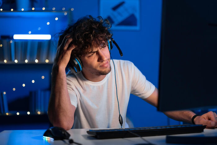 Man wearing headphones confused looking at computer