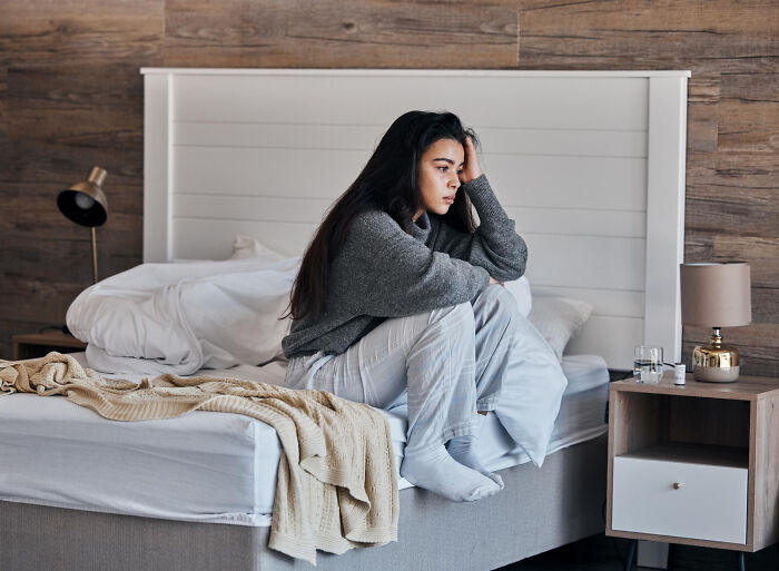 Woman sitting alone on bed looking sad and pensive, emotional aftermath of unhinged breakup excuses