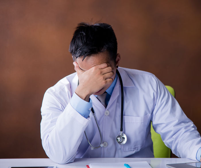 Frustrated doctor with head in hand during consultation