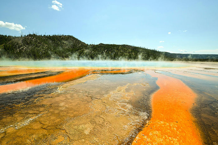 Colorful hot spring with steam rising in natural terrifying landscape
