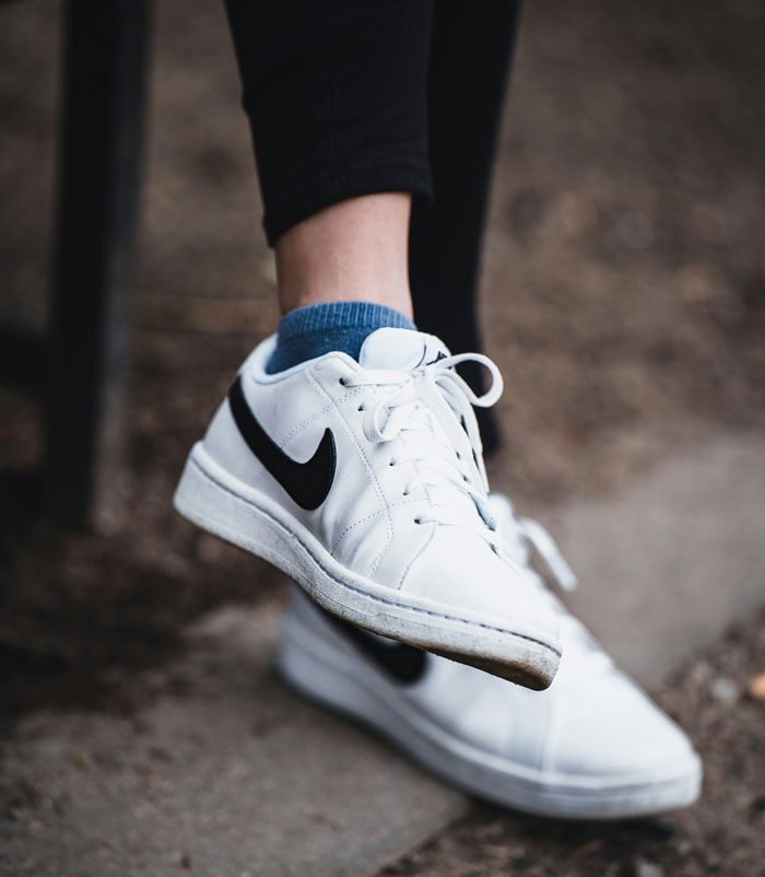 Close-up of person wearing white Nike sneakers with black swoosh