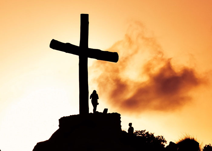 A silhouette of a person standing by a large cross, symbolizing the end of a popular kid's high school peak.