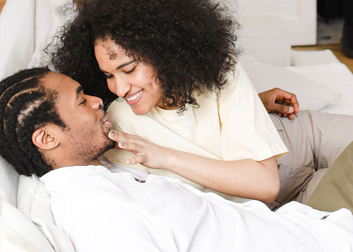A happy couple in bed, symbolizing things close friends commit that broke people's trust forever.