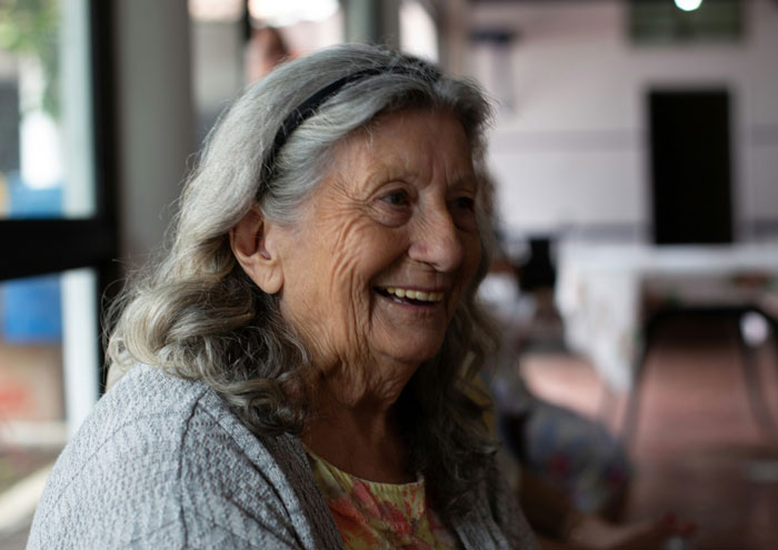 A happy older woman with gray hair smiling, reflecting a positive DNA testing story.