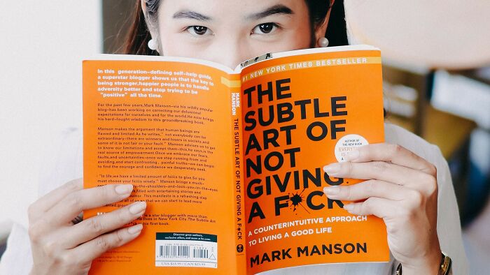 A person holds open a book, The Subtle Art of Not Giving a F*ck, related to acceptable actions on a date.