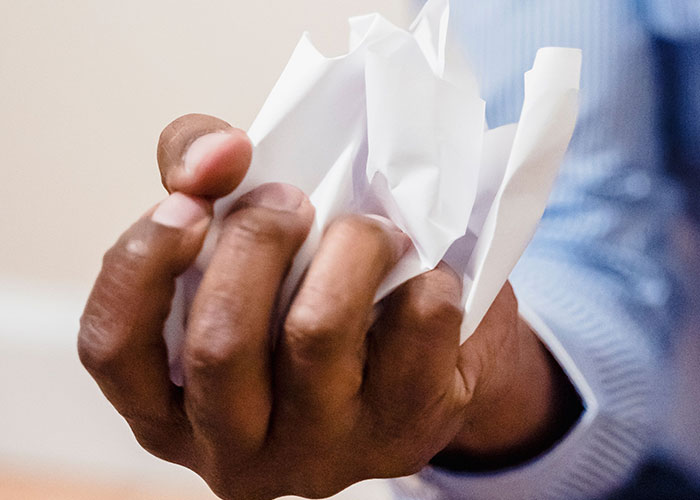 A hand crushing a piece of paper, representing the frustration of family expectations and advice.