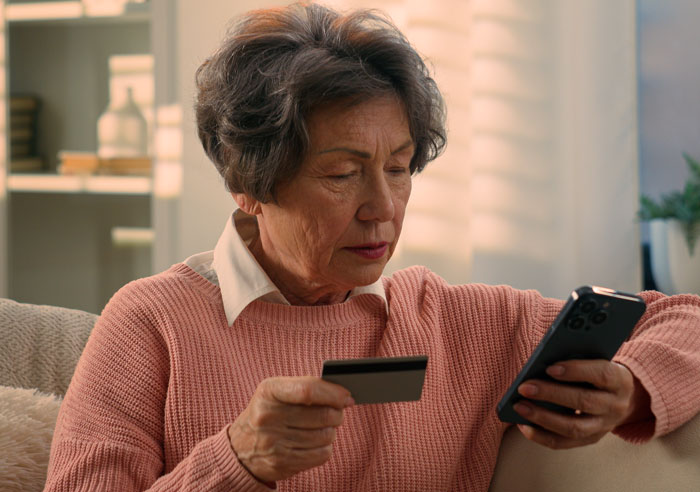An elderly woman holding a credit card and a smartphone. Heartwarming things people saw on their late parents' phones.