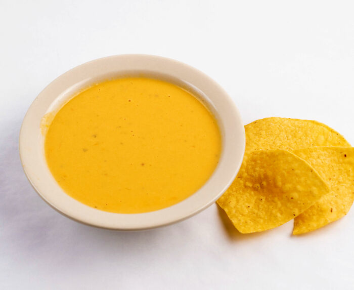 A bowl of cheese dip with tortilla chips, a cool, interesting, and surprising fact about snacks.