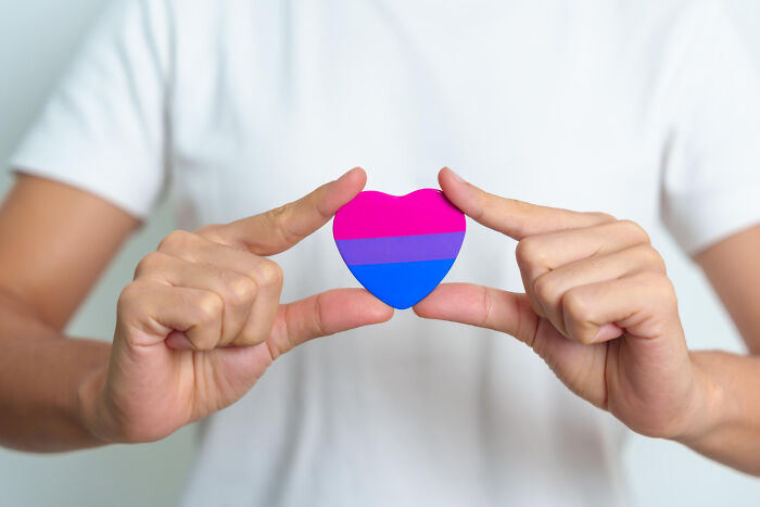 Hands holding a heart in bisexual pride flag colors, symbolizing disturbing things people learn about friends.
