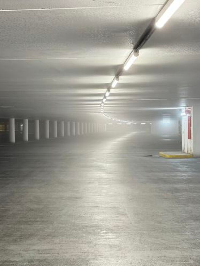 A long, foggy underground parking garage with rows of pillars, illustrating a haunting liminal space.