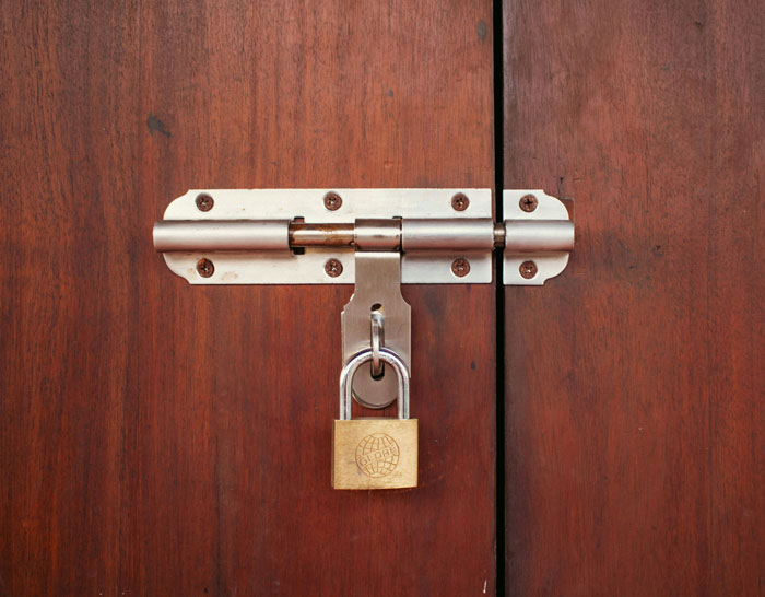 Close-up of a padlocked latch on a wooden door Close-up of a padlocked latch on a wooden door