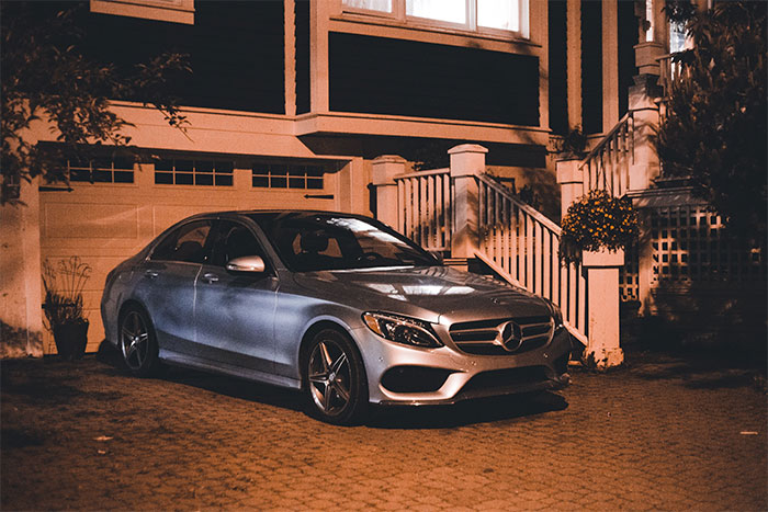 A nice car parked outside a house at night, related to a woman told to leave home.