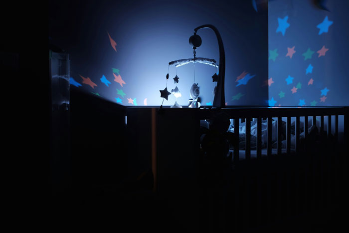 Baby crib with hanging star mobile illuminated by blue light