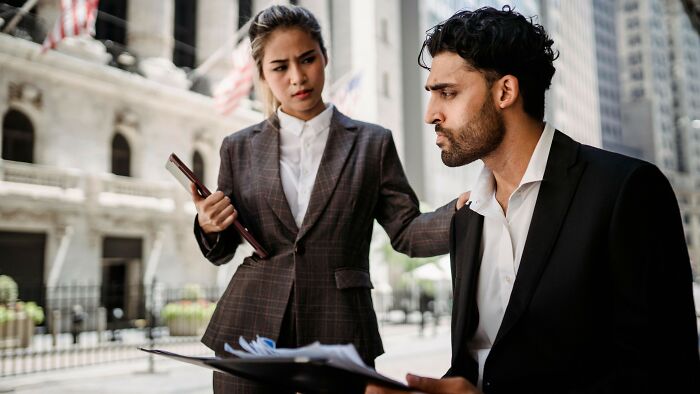 Businesswoman offering support to stressed man with documents on city street