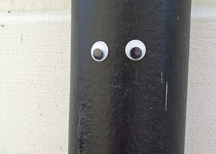 Googly eyes affixed to a black pipe, showing unserious solutions to serious problems.