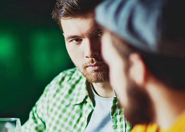 A man looking intently at another person, suggesting the complexity of relationships when family isn't everything.