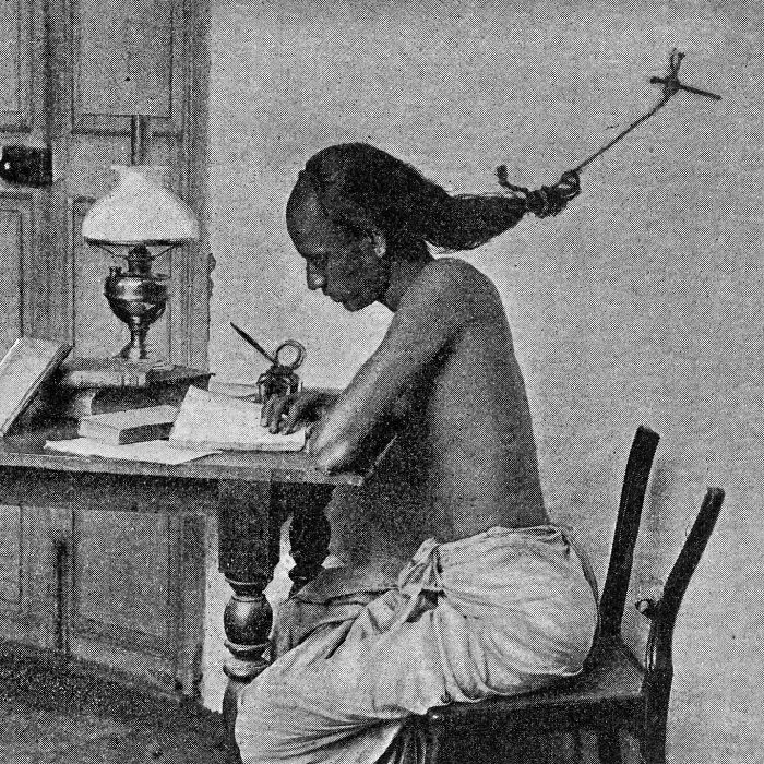 An interesting historical photo showing a man studying at a desk with an invention to keep him awake.