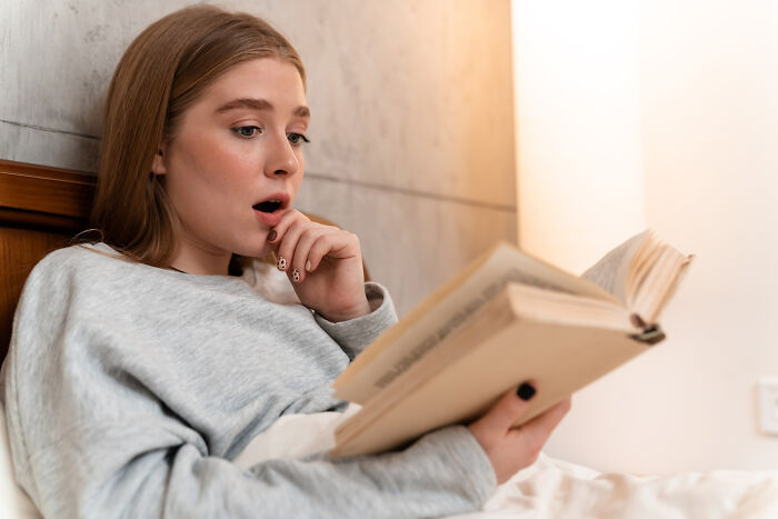 Surprised woman reading a book with shocked expression on face
