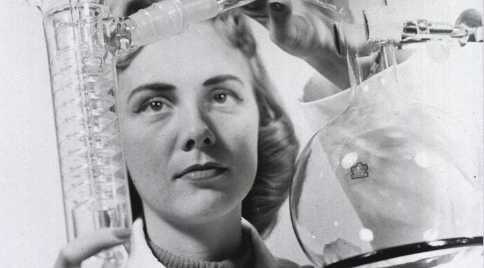 Vintage female scientist conducting chemistry experiment with glass lab equipment Vintage female scientist conducting chemistry experiment with glass lab equipment