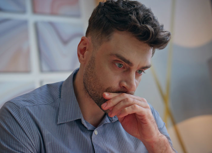 Pensive man appearing deep in thought about padlocked spare bedroom mystery Pensive man appearing deep in thought about padlocked spare bedroom mystery