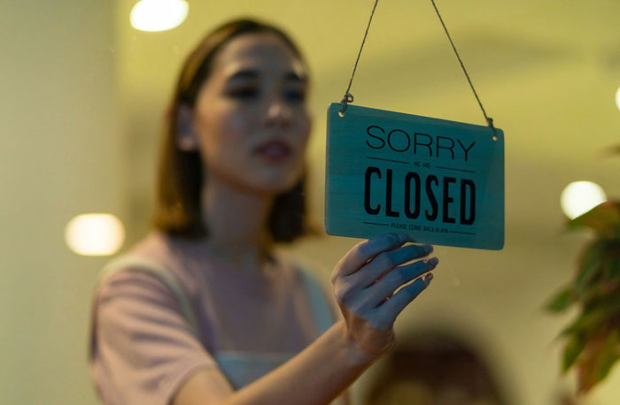 Woman holding a closed sign at a store entrance