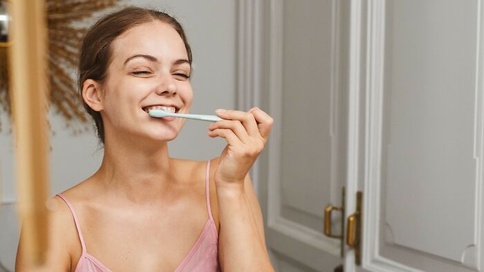 Smiling woman brushing teeth symbolizing personal care and moral dilemma reflection