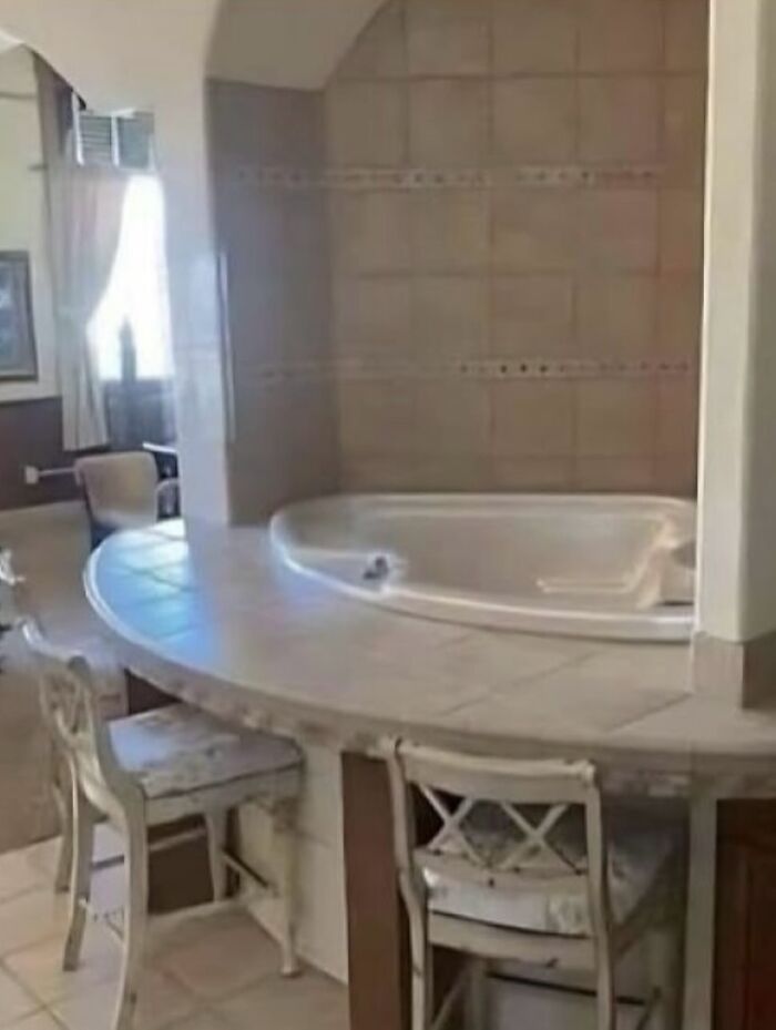 Bathtub surrounded by kitchen-style chairs and counter creating design fail