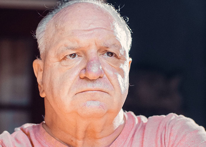 A close-up of an elderly man with a serious expression, pondering moments when kids cant keep contact with parents.