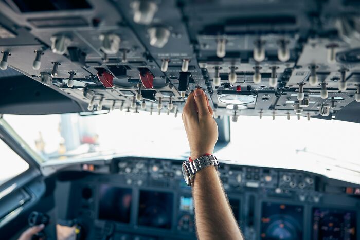 A pilot's hand adjusting controls in a cockpit, demonstrating plane interactions.