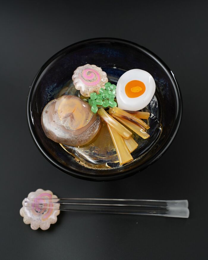 Hyper-realistic glass ramen bowl with glass chopsticks, looking good enough to eat.