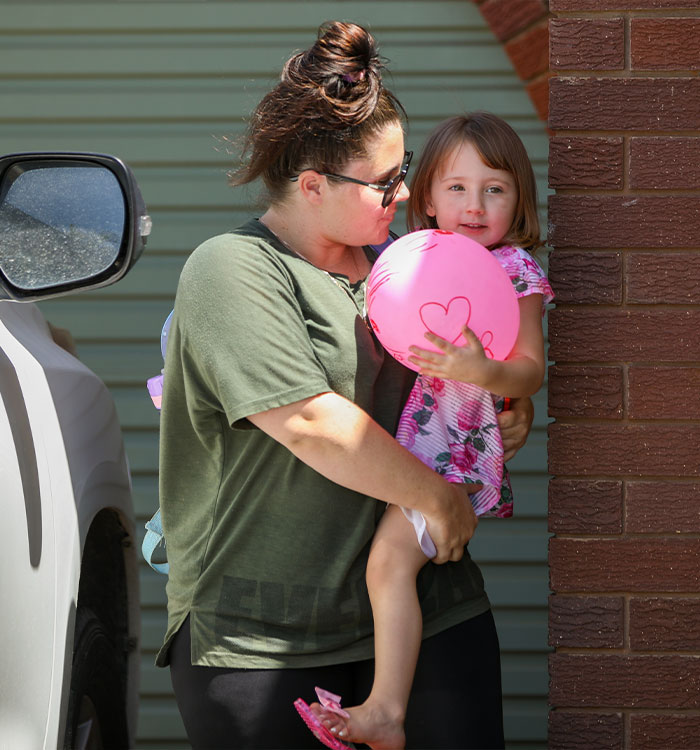 Mother carrying 4-year-old girl holding pink heart balloon Mother carrying 4-year-old girl holding pink heart balloon
