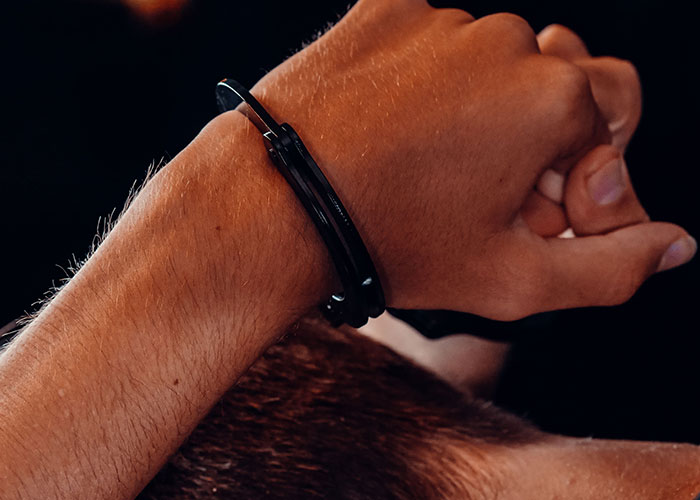 A hand wearing a black bracelet-like object, an unserious solution to an unknown problem.