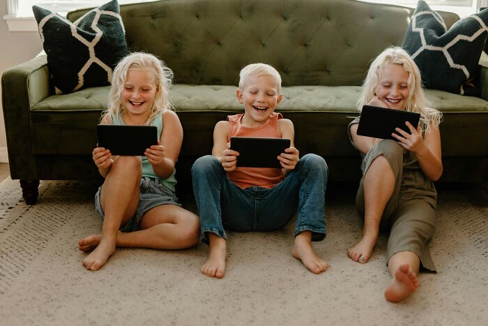 Three kids laughing while looking at tablets, unrelated to plane interactions.
