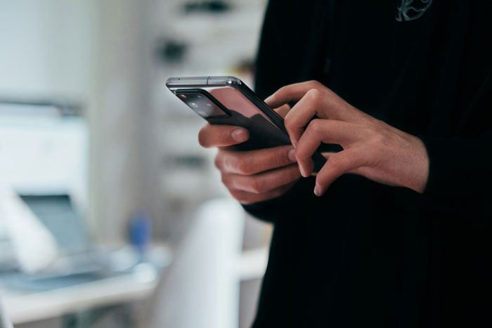 Hands holding a smartphone. Heartwarming and heartbreaking things people saw on their late parents' phones.
