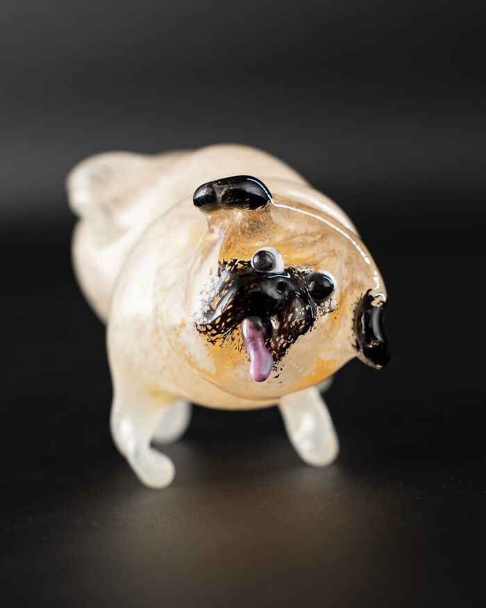 Japanese artist's hyper-realistic glass food sculpture of a pug dog on a black background.