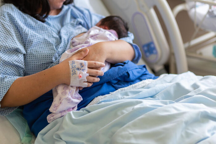 Mother holding newborn baby in hospital bed after birth