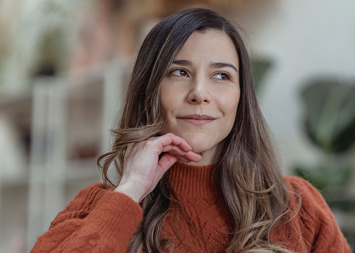 Thoughtful woman in orange sweater pondering, wild secrets concept