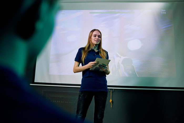 Woman giving a presentation using a tablet in front of a screen