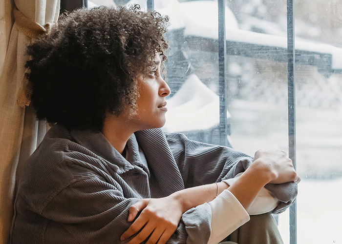 Thoughtful person looking out window reflecting on life mistakes