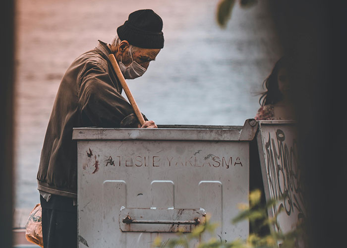 Man wearing mask searching through a dumpster as a legal offense example