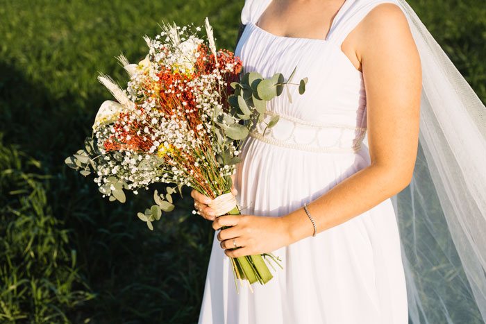 Bride in white dress holding rustic wedding bouquet outdoors