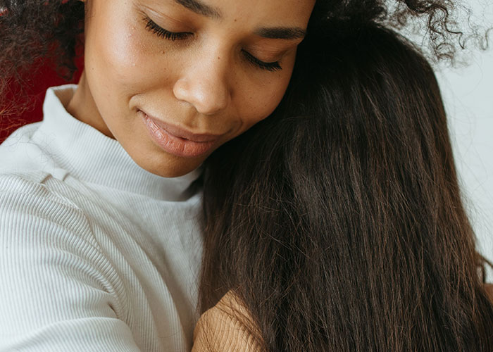 A woman embracing another person, showing emotional support for kids who can’t keep contact with their parents.