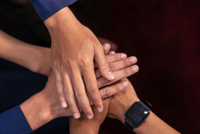 Multiple hands stacked together, representing the connections and revelations from DNA testing stories.