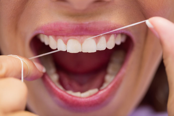 Close-up of person flossing teeth for dental care