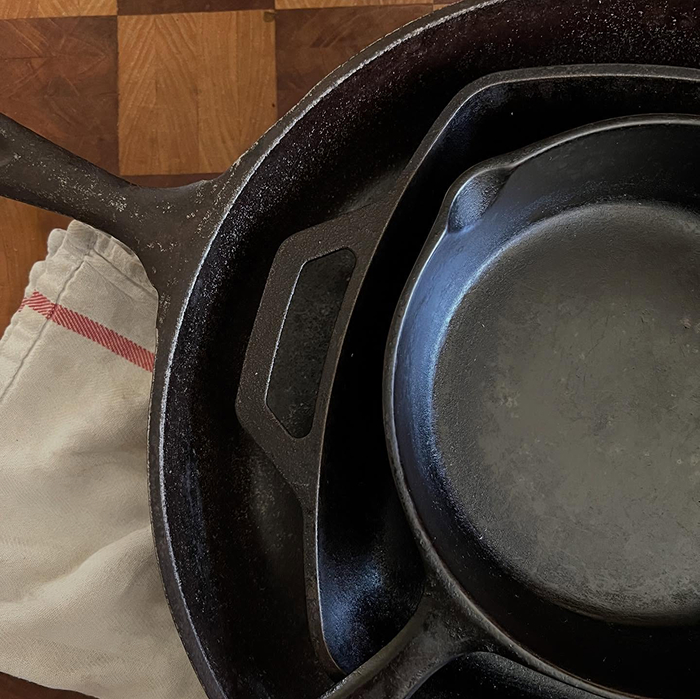 Stacked cast iron skillets on wooden surface for cooking myths