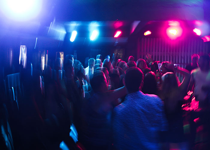 Crowd dancing in a dark room with colorful party lights