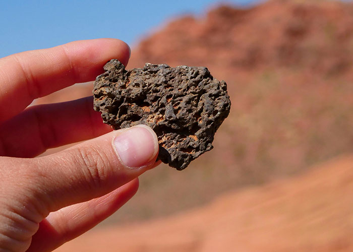Hand holding a rough rock outdoors, symbolizing legal offense actions