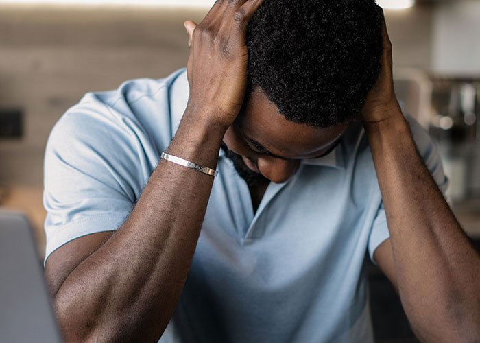 Man sitting with head in hands showing stress or frustration