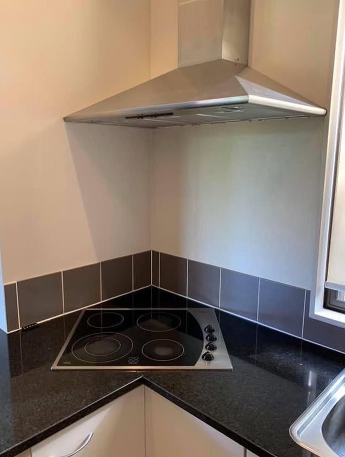 Kitchen stovetop placed in corner under a large hood causing impractical design fail