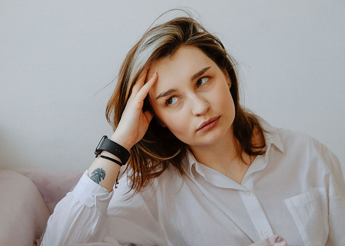 A woman with a pensive expression, thinking about horrible things committed by close friends that broke her trust.